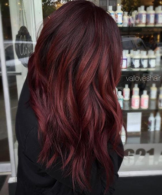 Transform your look with dark red velvet-inspired burgundy red hair. Achieve a deliciously captivating style with a rich shade that blends seamlessly in a balayage effect.