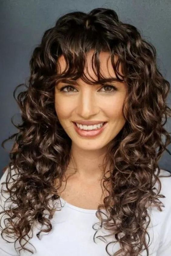 Wolf cut curly hair with bangs highlighting natural curls