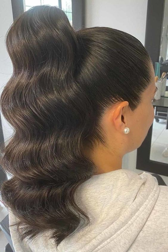 High ponytail wrapped with a section of hair for a polished and seamless look, emphasizing elegance and style.