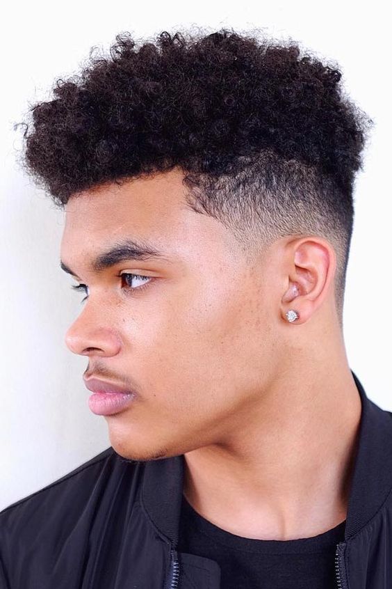 Curly high top fade hairstyle for men, with a high, rounded top and faded sides.