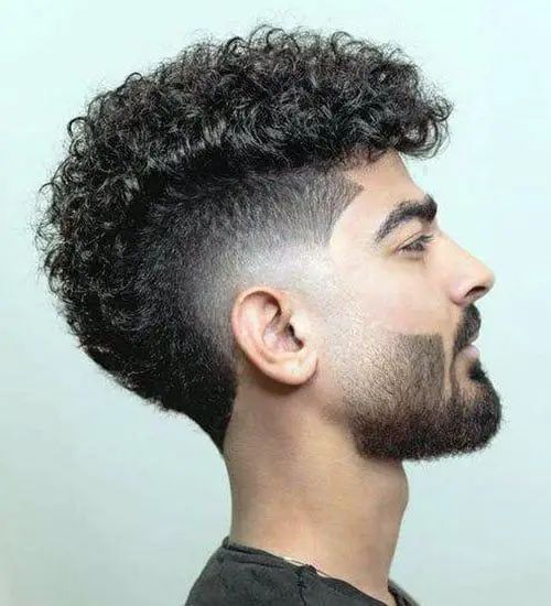 Man with a curly Mohawk showcasing natural curls on top and short sides.