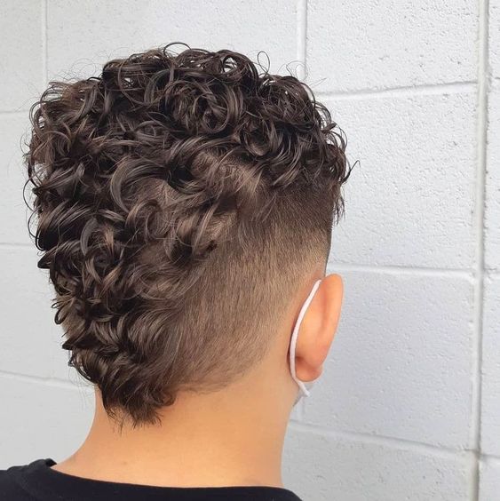 Man sporting a faux hawk hairstyle with a subtle, tapered side and raised center.